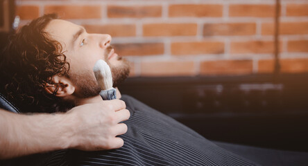 Barber shaving man with sharp steel razor, banner barbershop warm retro old toning