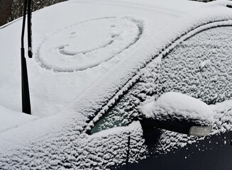 A snow covered car with a smiley face on it