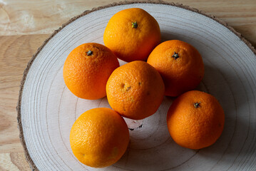 oranges citrus displayed on a wooden log chopping board