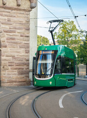 Portrait orientation shot of a green tram travelling through the streets of Basel, Switzerland on a...