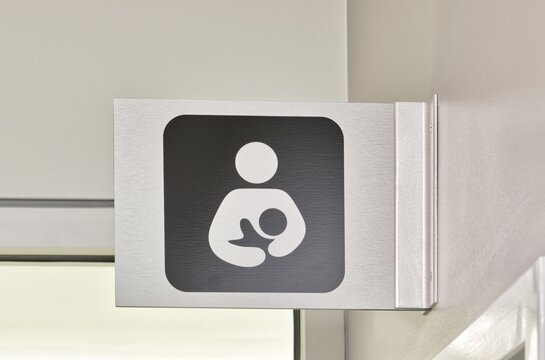 Nursing Room sign made of metal, above a doorway in an office environment. Special room for mothers of infant children to tend to their needs.