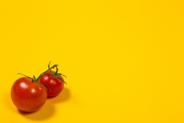 Red cherry tomatoes on a yellow background