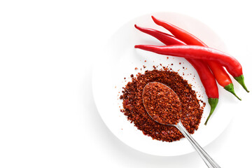 Dry red chilli pepper flakes with fresh chillies on a white plate. Flat lay top view photo. 