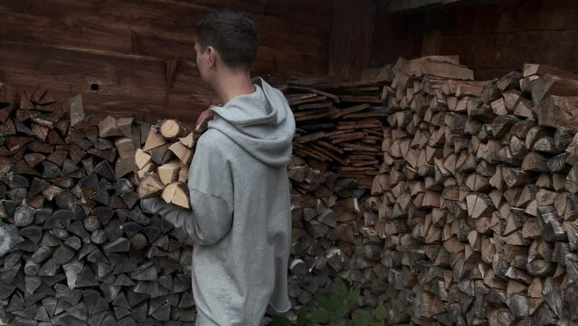 A man stacking firewood and preparations for the winter. Authentic look of a mountain village