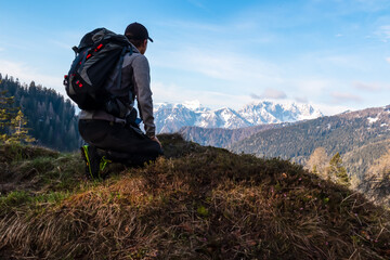 Hiker man with scenic view of snow covered mountain range Julian Alps seen from Karawanks in...