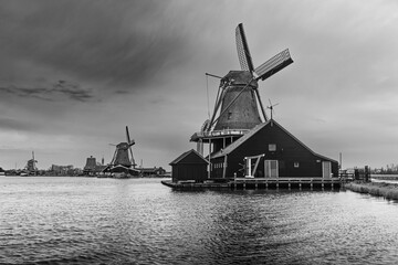 Black and white image of iconic windmills by the water in the historic village of Zaanse Schans, Netherlands