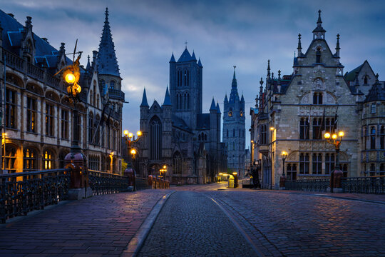 Historical buildings and street lights at dawn in Ghent with Saint Bavo's Cathedral in the background