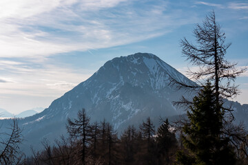 Scenic view on mountain peak Mittagskogel (Kepa) in Karawanks mountains in Carinthia, Austria. Looking through dense forest. Misty and magical atmosphere in remote landscape in Slovenian Austrian Alps