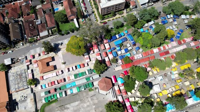 To down aerial drone view of stands in the Feira do Alto in Teresopolis, Rio de Janeiro, Brazil with a reveal of the surrounding landscape