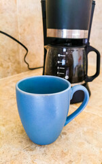 Blue coffee cup and black coffee maker from Mexico.