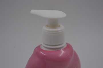 Body care products, facial skin care cosmetics, a bottle with a white liquid soap dispenser placed on a white, plastic background.