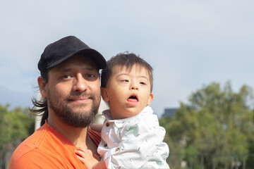 Portrait of father and son with down syndrome looking at camera in a Park