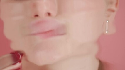 In the close up shot on a pink background is a young girl. She is allegedly underwater, touching her fingers with manicure to her lips. At this time, the water sends waves blurring its image