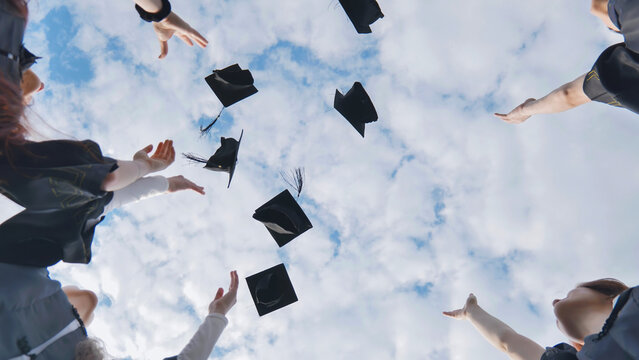 Happy college graduates tossing their caps up at sunset.