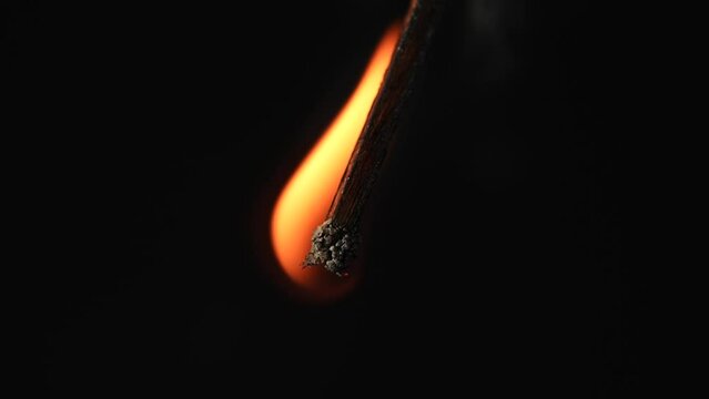 The burning match demonstrates a smooth extinguishing, dims, disappearing beneath the smoke. The process symbolizes the end, the fading out and the transition to silence and tranquility. Macro.