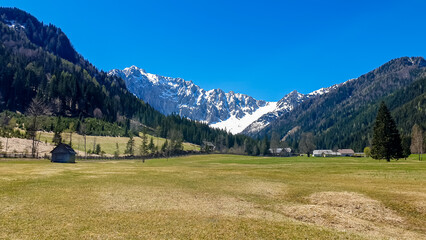 Alpine meadow of the Maerchenwiese with panoramic view of Karawanks mountains in Carinthia, Austria. Looking at snow capped summit of Vertatscha and Hochstuhl. Remote alpine landscape in Bodental