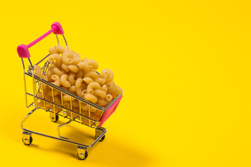Pasta in a shopping cart on a yellow background