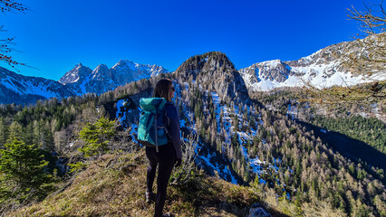 Hiker woman enjoying scenic view of Karawanks mountain range in Carinthia, Austria. Looking at snow capped summit of Vertatscha and Hochstuhl. Remote alpine landscape in Bodental, Austrian Alps
