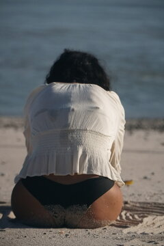 A young woman in a straw hat sits on the beach in Costa Rica