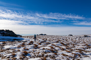 Woman with hiking backpack walking on snow covered alpine meadow on trail from Ladinger Spitz to...