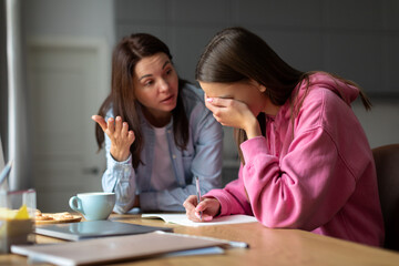 Angry mother scolding teen daughter for bad school results at home, mom arguing disciplining child must study. Parent and children conflicts concept