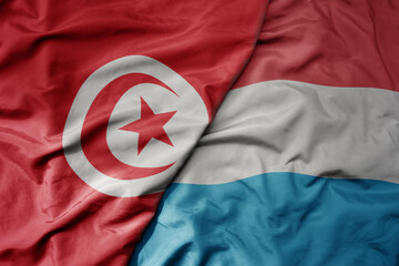 big waving national colorful flag of luxembourg and national flag of tunisia .