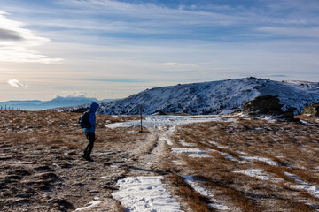 Man with backpack hiking in cold windy winter at Ladinger Spitz in the Saualpe mountain range,...