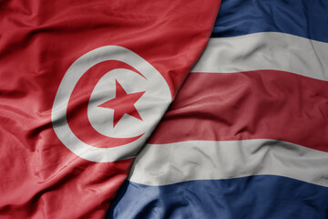 big waving national colorful flag of costa rica and national flag of tunisia .