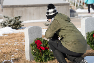 person laying a wreath on a gravesite