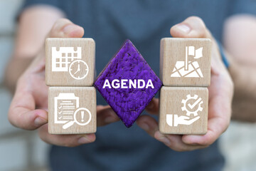 Man holding multi-colored blocks with icons sees word: AGENDA. Agenda meeting appointment activity...