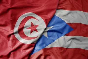 big waving national colorful flag of puerto rico and national flag of tunisia .