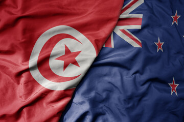 big waving national colorful flag of new zealand and national flag of tunisia .