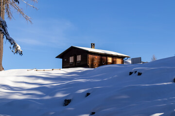 Scenic view of small wooden cabin Bertahuette nestled in the snowy mountains of Karawanks, Carinthia, Austria. Winter wonderland in Austrian Alps. Ski touring trail to Mittagskogel. Luxury cottage