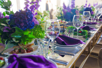 Beautiful festive table setting with flowers and purple napkins. 