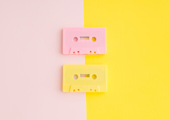 Layout of retro pink and yellow audio cassette tapes on pastel  pink and yellow background....