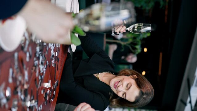 vertical video beautiful smiling woman holding a sparkler during a birthday celebration in a restaurant in the company of friends