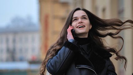 Beautiful stylish brunette girl talking on the phone on the street