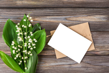 Blank greeting card with spring Lily of the valley flowers bouquet on rustic wooden background. Wedding invitation. Womens day, Valentines day card. Mock up. Flat lay