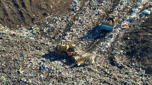 Solid waste disposal facility. Landfill dump site for garbage management. Bulldozer tractors burying large amount of trash under the ground