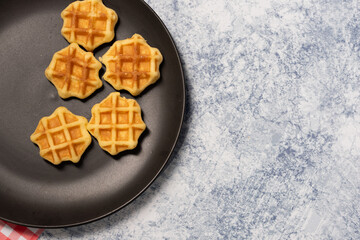 waffles on a black plate set on a marble blue background