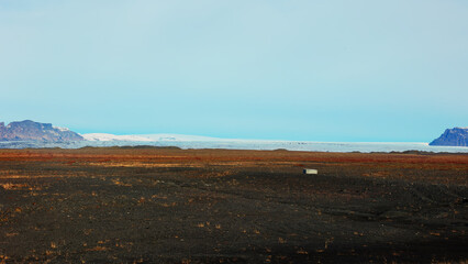 Beautiful countryside scenery with field and white snowy mountains on roadside, scandinavian landscapes with frozen hills. Fantastic icelandic nature with panoramic view. Handheld shot.