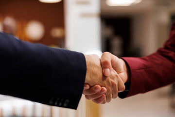 Entrepreneurs agreeing upon collab together, successful important meeting at hotel abroad. Business professionals shaking hands to mark the beginning of a fruitful partnership. Close up. - obrazy, fototapety, plakaty