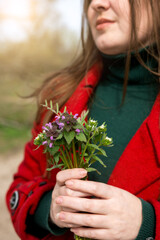 a woman of Slavic appearance holds a bouquet of wild spring flowers in her hands