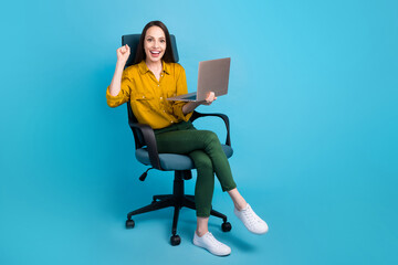 Full length photo of positive lucky woman dressed yellow shirt winning game modern device empty space isolated blue color background