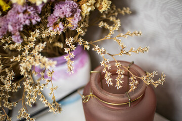 Close-up of blooming purple, white and yellow small flowers in vase. Dried flowers or ikebana for interior decoration.