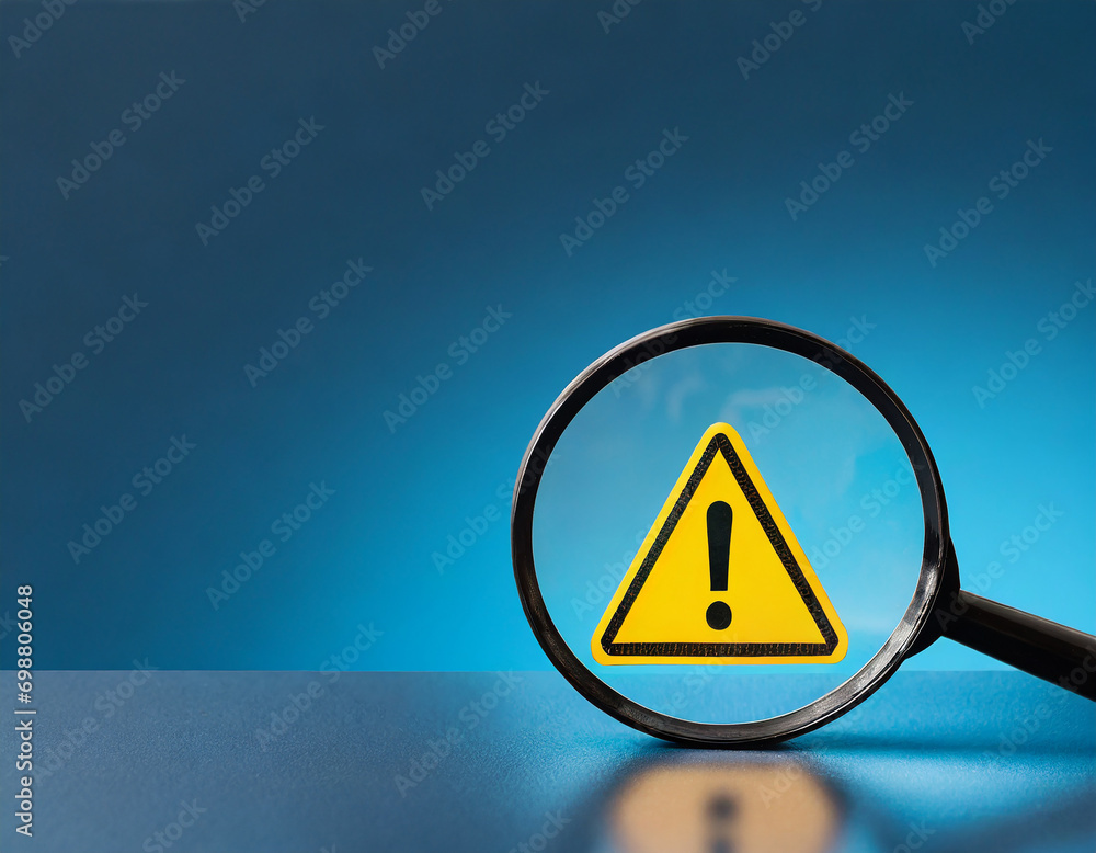 Poster yellow triangle caution warning sign inside of magnifier glass on blue background and copy space for