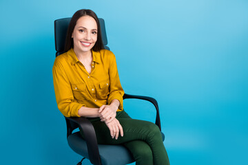 Photo of positive good mood woman dressed yellow shirt sitting armchair empty space isolated blue color background