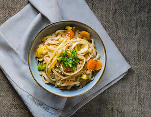 Cooked dish of udon noodles with vegetables on the table on textiles