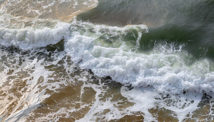 Fototapeta premium On the sea, a foaming wave rolls up to the shore, top view