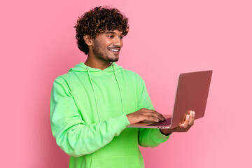 Photo of young man wear green sweatshirt choosing surfing internet using netbook best black friday deals isolated on pink color background